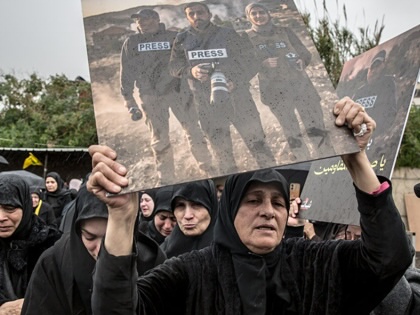 A woman holds up a poster of three journalists killed the previous day by Israeli air strikes, during their funeral ceremony in Choueifat, south of Beirut.