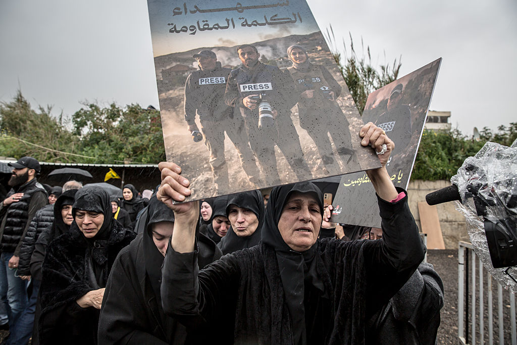 A woman holds up a poster of three journalists killed the previous day by Israeli air strikes, during their funeral ceremony in Choueifat, south of Beirut.