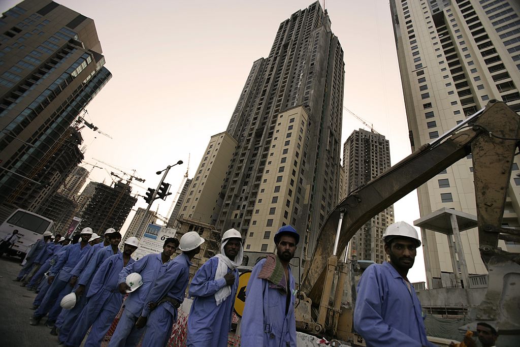 Migrant workers in the construction industry wait for their buses at the end of their working day on May 1, 2006, in Dubai, United Arab Emirates. 