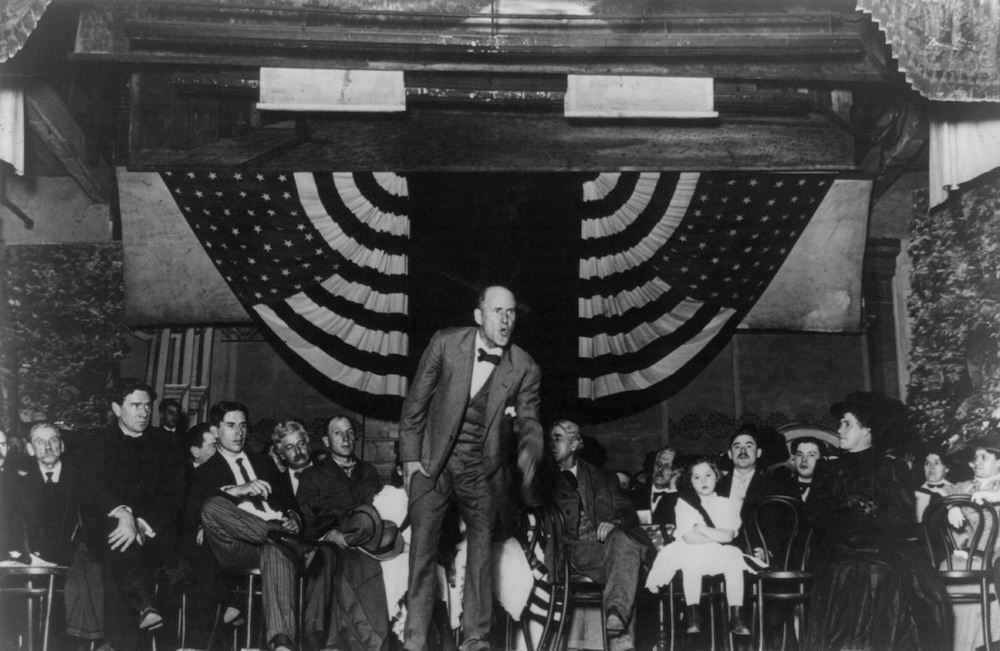 Eugene V. Debs addresses a crowd in front of an American flag.