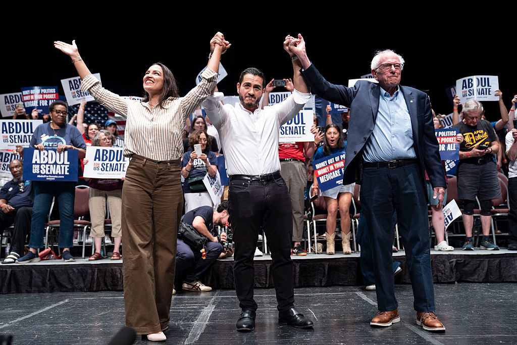 (L-R) U.S. Rep. Alexandria Ocasio-Cortez (D-NY), Michigan Democratic candidate for Senate Abdul El-Sayed and U.S. Sen. Bernie Sanders (I-VT) greet the crowd after El-Sayed spoke at The People V. The Powerful rally at the Detroit Opera House on July 18, 2026, in Detroit, Michigan.