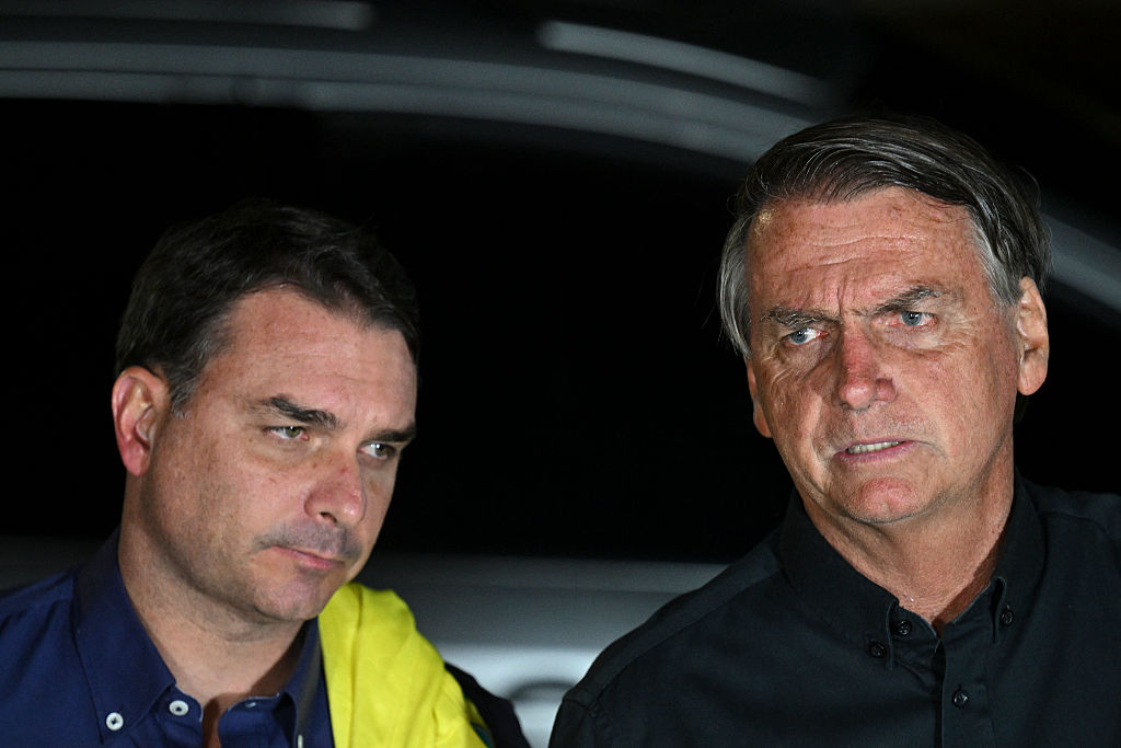 Jair Bolsonaro speaks next to his son Flávio in Brasilia, on October 2, 2022.
