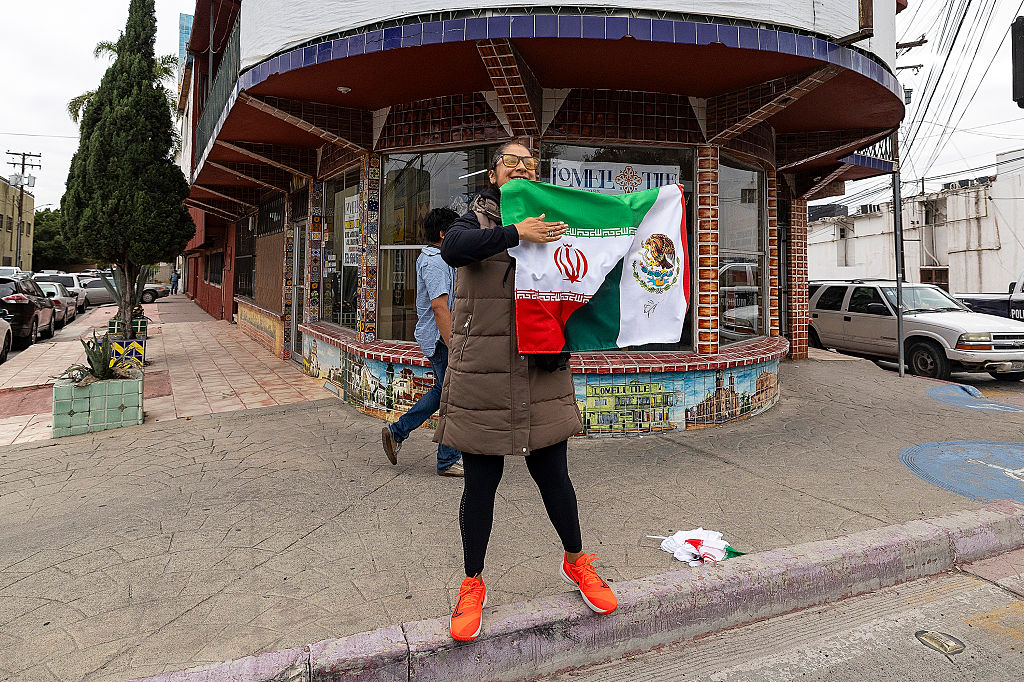 A soccer fan in Tijuana, Mexico, holds a flag of Iran and Mexico and bids farewell to the players of Iran after it participated in the 2026 World Cup.