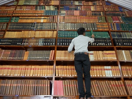A librarian looks for a book on a shelf inside the library at the Kodaikanal Solar Observatory on June 20, 2025, in Kodaikanal, India.
