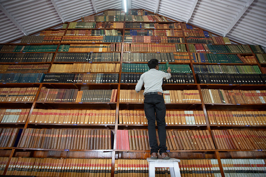 A librarian looks for a book on a shelf inside the library at the Kodaikanal Solar Observatory on June 20, 2025, in Kodaikanal, India. 