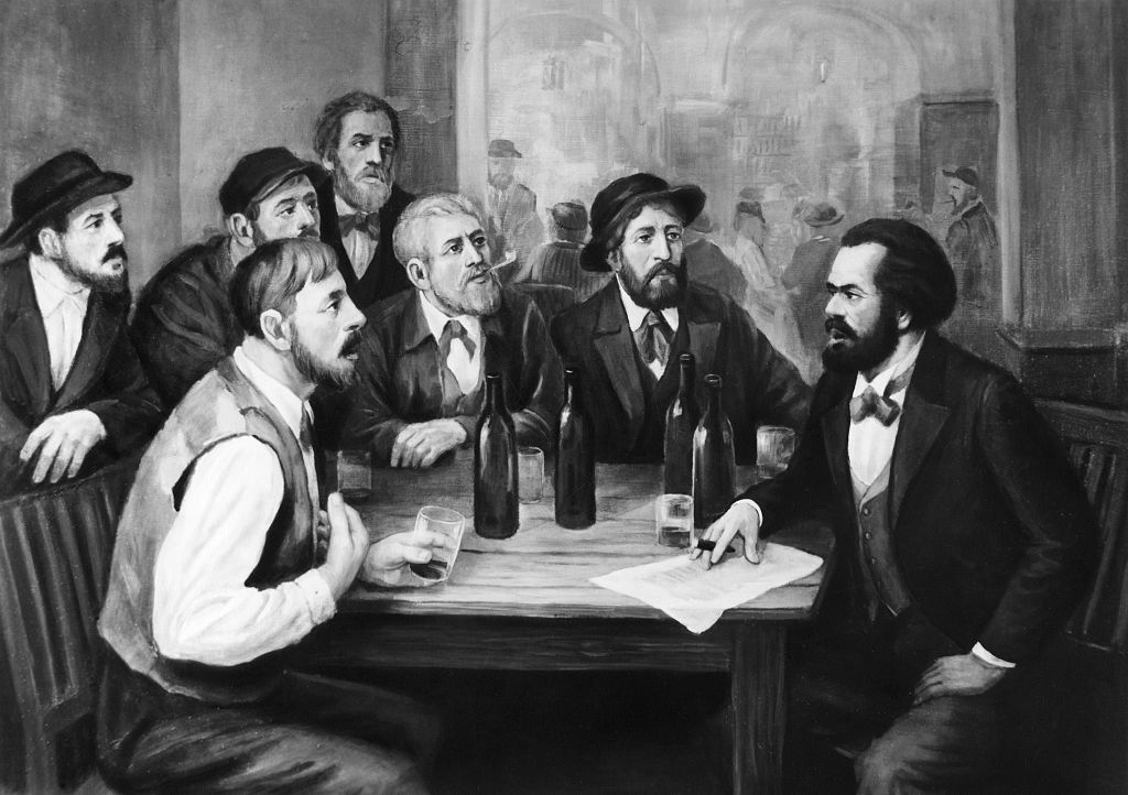 An illustration of Karl Marx speaking to a group of men at a tavern.