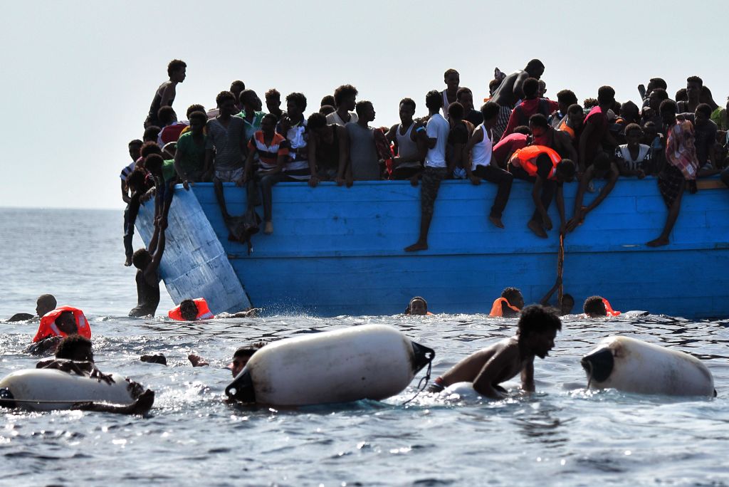 Migrants wait to be rescued by members  as they drift in the Mediterranean Sea, some 12 nautical miles north of Libya, on October 4, 2016.