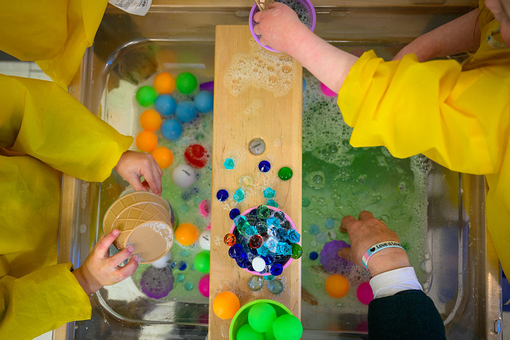 Students play with toys in a basin of soapy water at the Connecticut State University Early Learning Center on March 12, 2025, in New Britain, Connecticut.