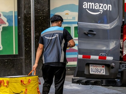 An Amazon worker holds a delivery bag near a delivery vehicle in San Francisco, California, US, on Monday, Feb. 2, 2026.