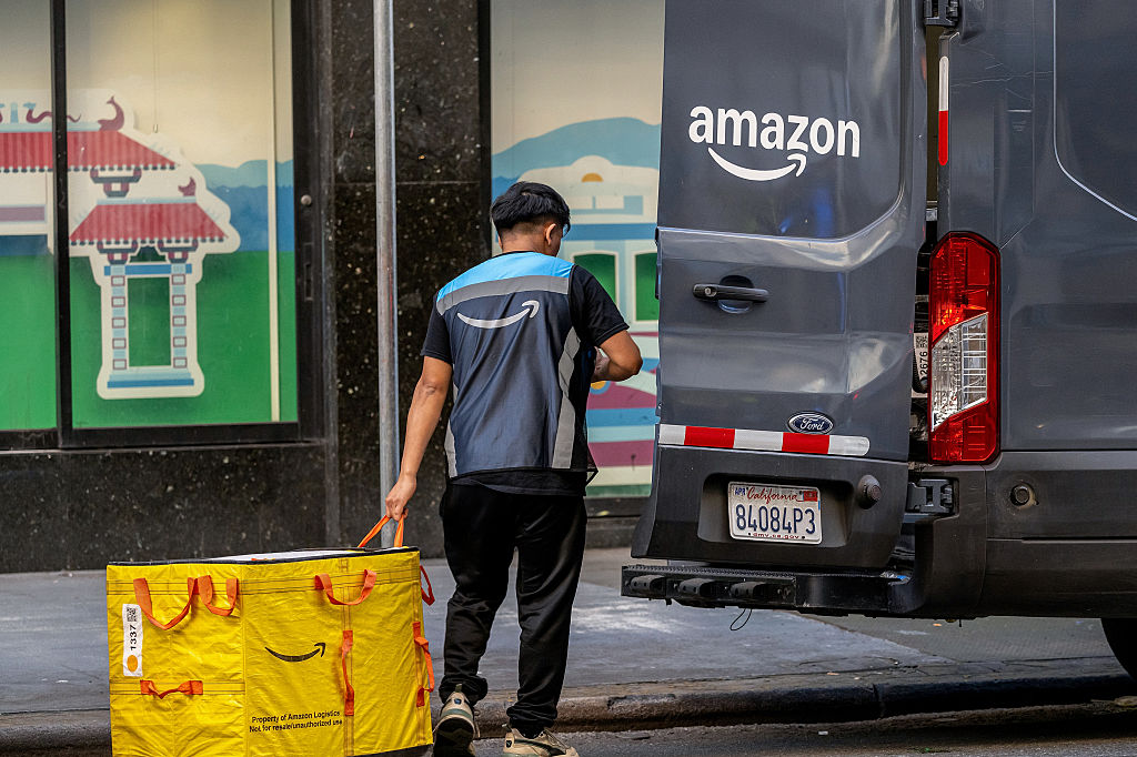 An Amazon worker holds a delivery bag near a delivery vehicle in San Francisco, California, US, on Monday, Feb. 2, 2026.