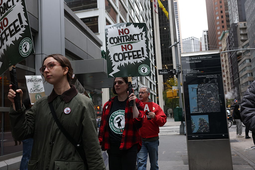 Starbucks baristas gather outside a Starbucks store as they protest against the company during a rally to demand a new contract in New York City on October 28, 2025.