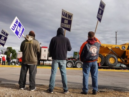 A truck hauls a piece of John Deere equipment from the factory past workers picketing outside of the John Deere Davenport Works facility on October 15, 2021, in Davenport, Iowa.