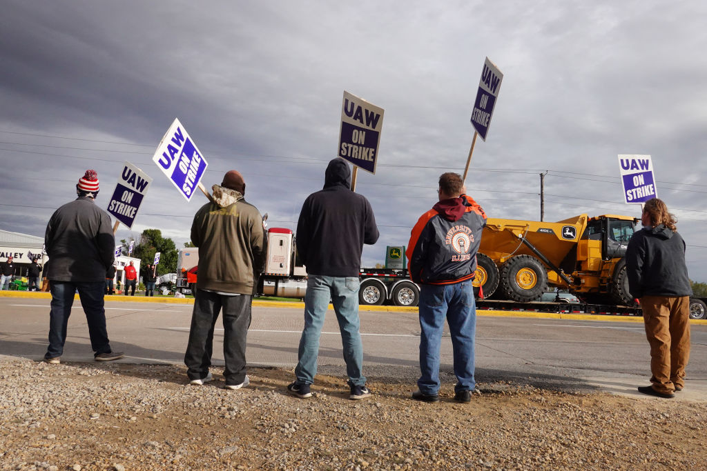 A truck hauls a piece of John Deere equipment from the factory past workers picketing outside of the John Deere Davenport Works facility on October 15, 2021, in Davenport, Iowa.