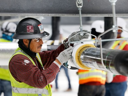 Construction workers build out the rooftop chillers and water lines feeding them atop Dallas TX4, which is under construction at the NTT Data center campus in Garland, Texas, March 4, 2026.