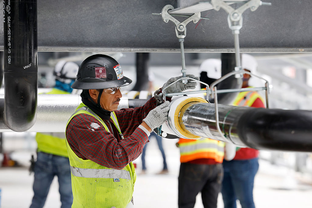 Construction workers build out the rooftop chillers and water lines feeding them atop Dallas TX4, which is under construction at the NTT Data center campus in Garland, Texas, March 4, 2026.