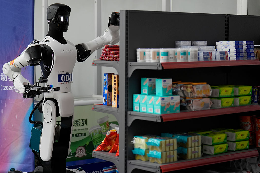 Robots simulate working on small supermarket shelves during the 2026 World Humanoid Robot Games in Beijing, China.