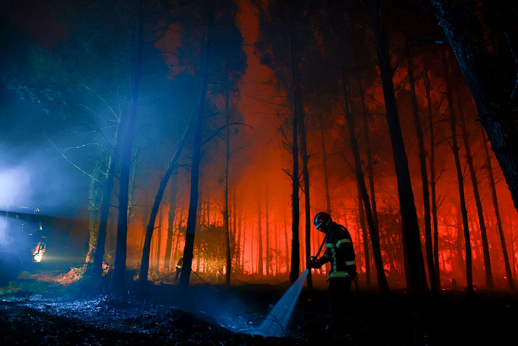 Un bombero riega con una manguera el suelo carbonizado mientras las llamas continúan ardiendo en el bosque de las Landas, en Luglon, Francia, el 14 de agosto de 2026.