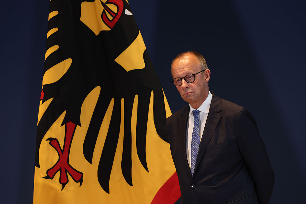 German Chancellor Friedrich Merz stands next to a flag showing the German federal eagle as he attends the dismissal and confirmation ceremony of government cabinet members on July 29, 2026, in Berlin, Germany. 