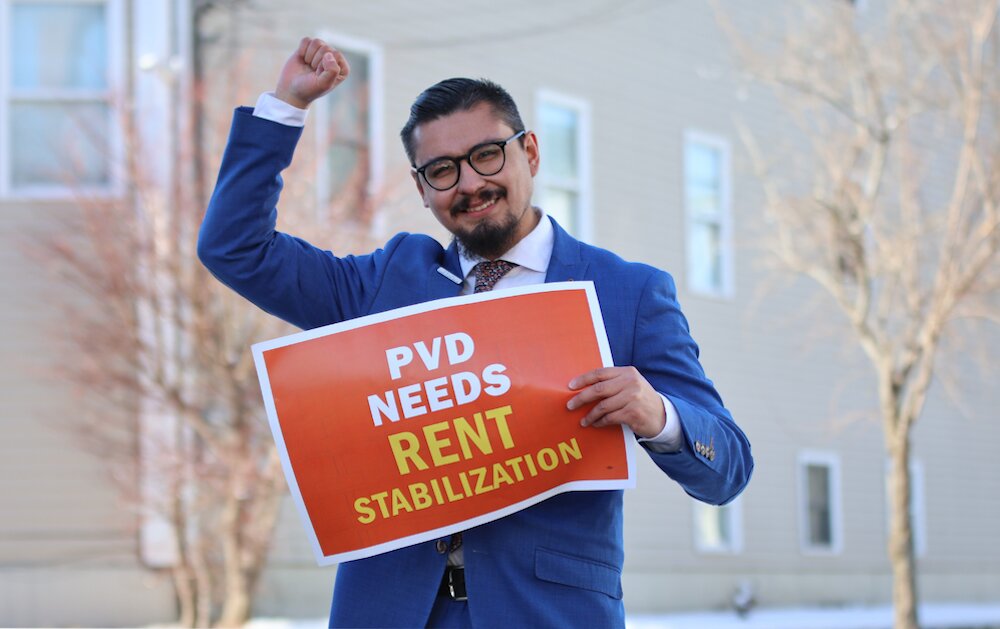 A campaign photo of David Morales holding a sign advocating rent stabilization.