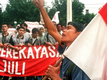 An Indonesian student holding the Indonesian national flag shouts antigovernment slogans while others hold a banner that says "Syarwan is the man behind the 27 July riot," during a protest at the Department of Home Affairs in Jakarta.