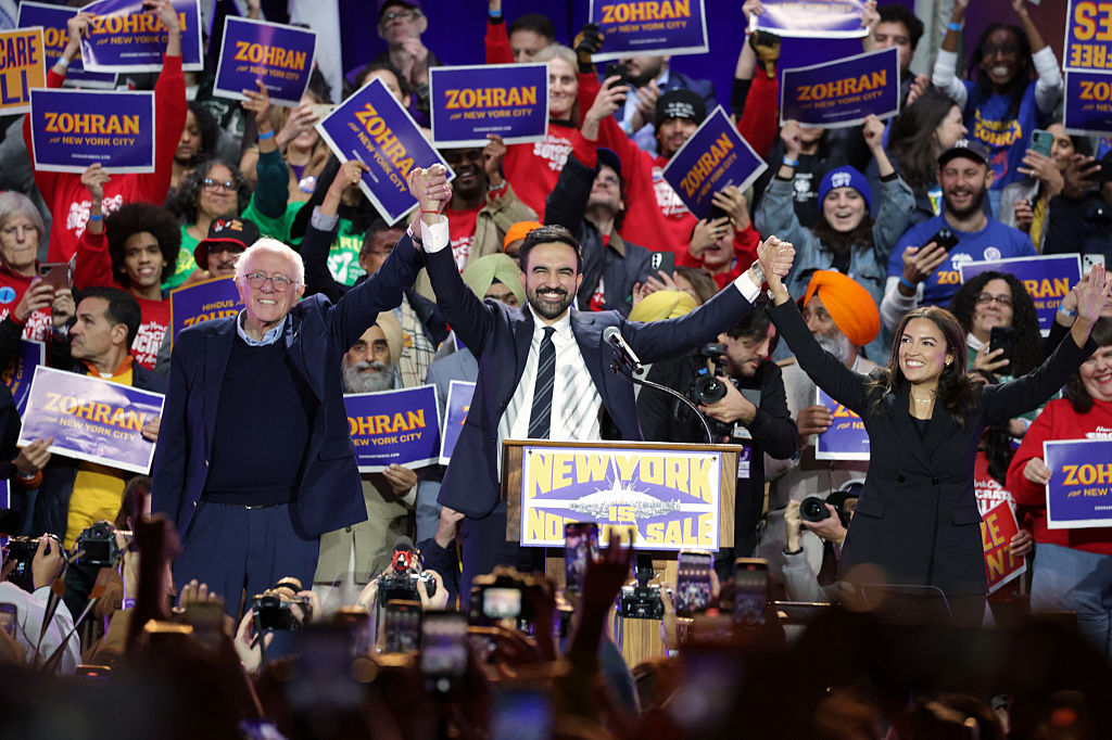 Then New York City mayoral candidate Zohran Mamdani holds hands with US Senator Bernie Sanders (I-VT) and US Representative Alexandria Ocasio-Cortez (D-NY) at the end of a campaign rally at Forest Hills Stadium in the Queens borough of New York City on October 26, 2025.