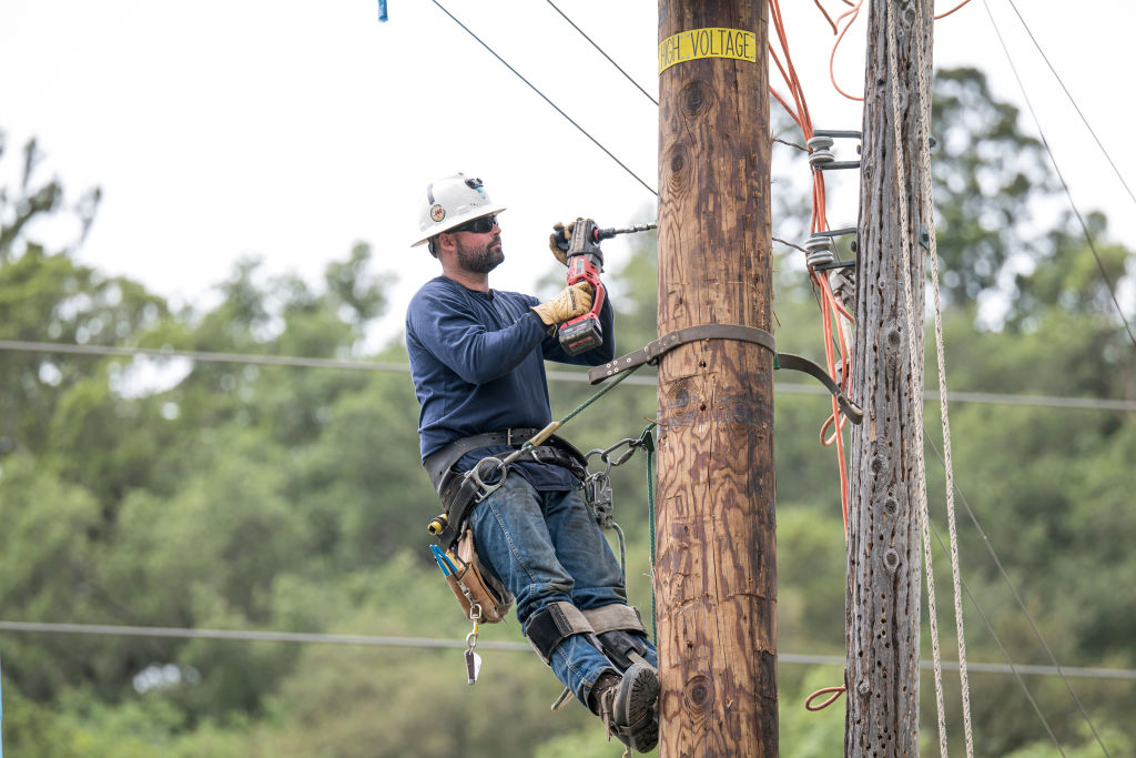A PG&amp;E worker drills a hole into a power pole in Yountville, California,  on April 29, 2020. 