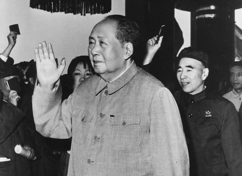 An elder Mao Zedong waves to a crowd, followed by Lin Biao.