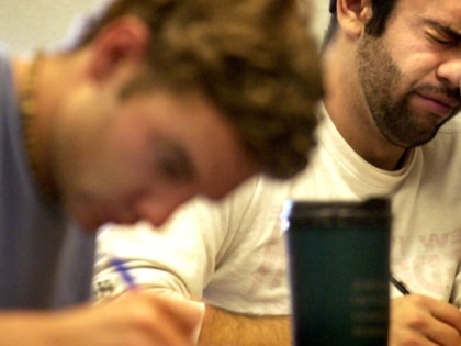 Two college students, one visibly exhausted, work at a desk.