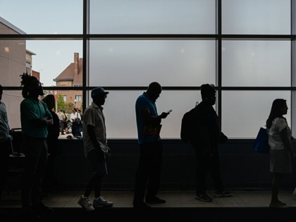 Job seekers wait in line to enter an auditorium for a job fair.