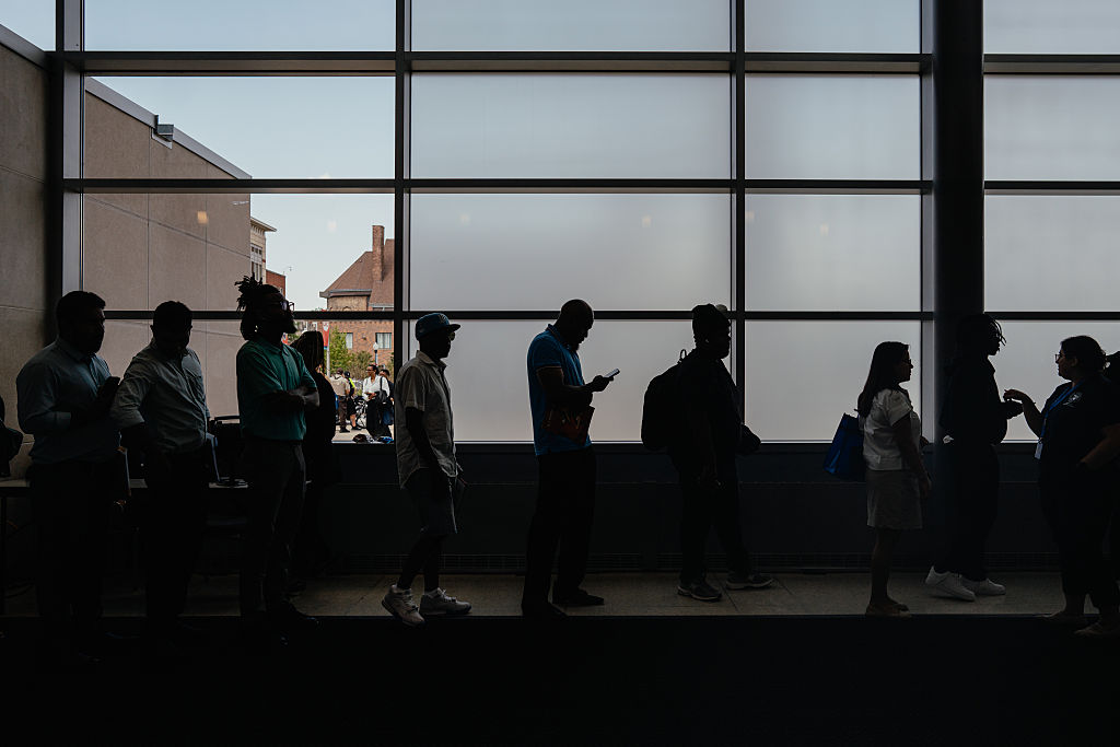 Job seekers wait in line to enter an auditorium for a job fair.